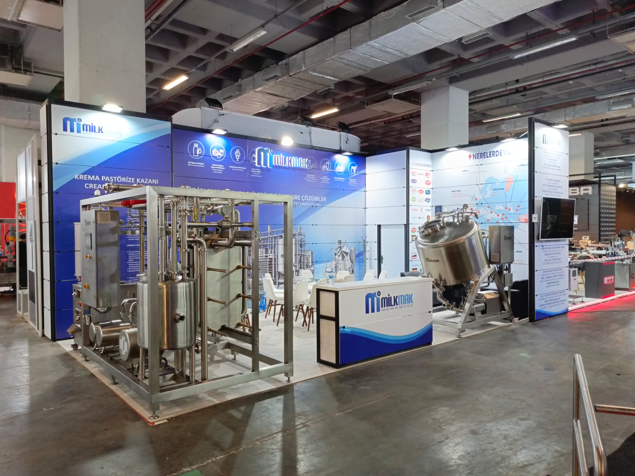 Milkmak fuar standının mavi beyaz panoları ve sergilenen makineleri